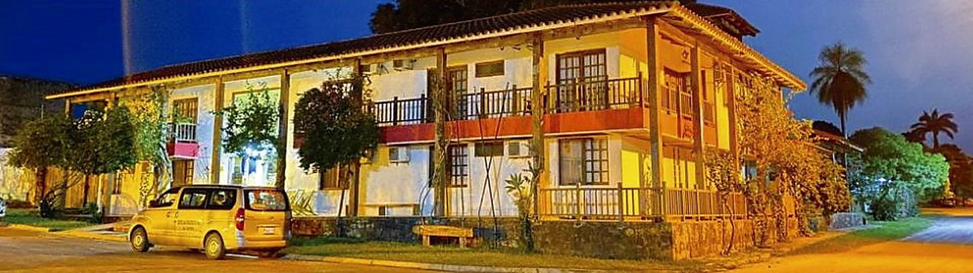 Fachada del Hotel Boutique Beula iluminada de noche, con sus dos plantas y balcones de madera